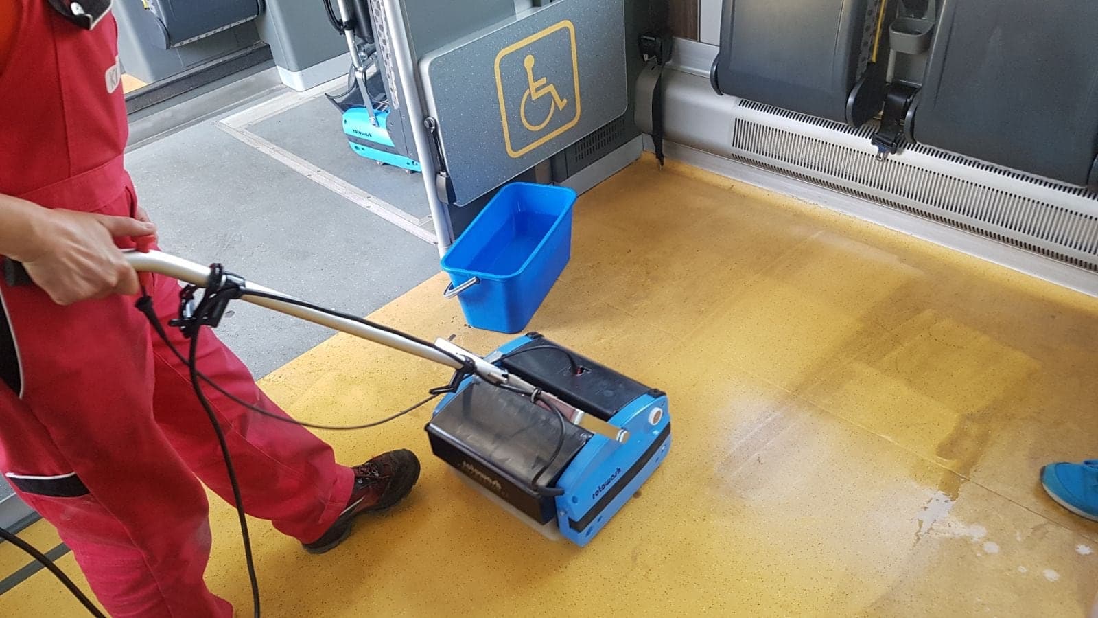 Operator czyści żółtą posadzkę przy rampie dla osób z niepełnosprawnością
